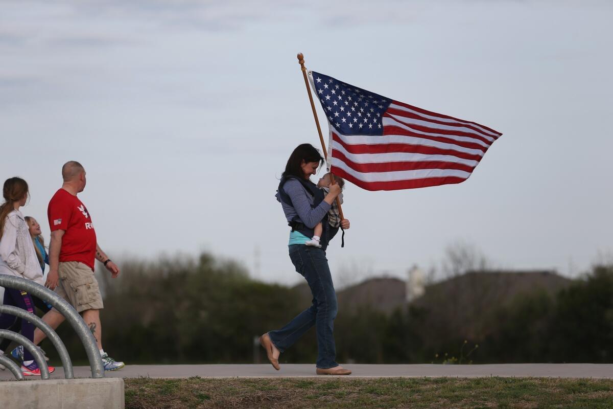 Mellissa Phillips holds Sierra Phillips as she and others participate in a flag walk in honor of those killed and injured by Spc. Ivan Lopez at Ft. Hood.