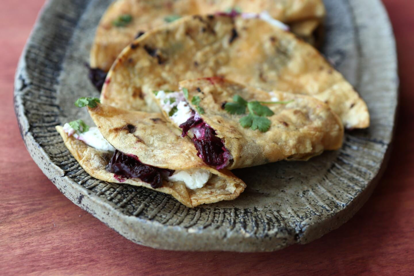 Tacos made with queso fresco, goat cheese, cilantro, cumin seeds, and hibiscus braised in chicken broth and chipotle chili.