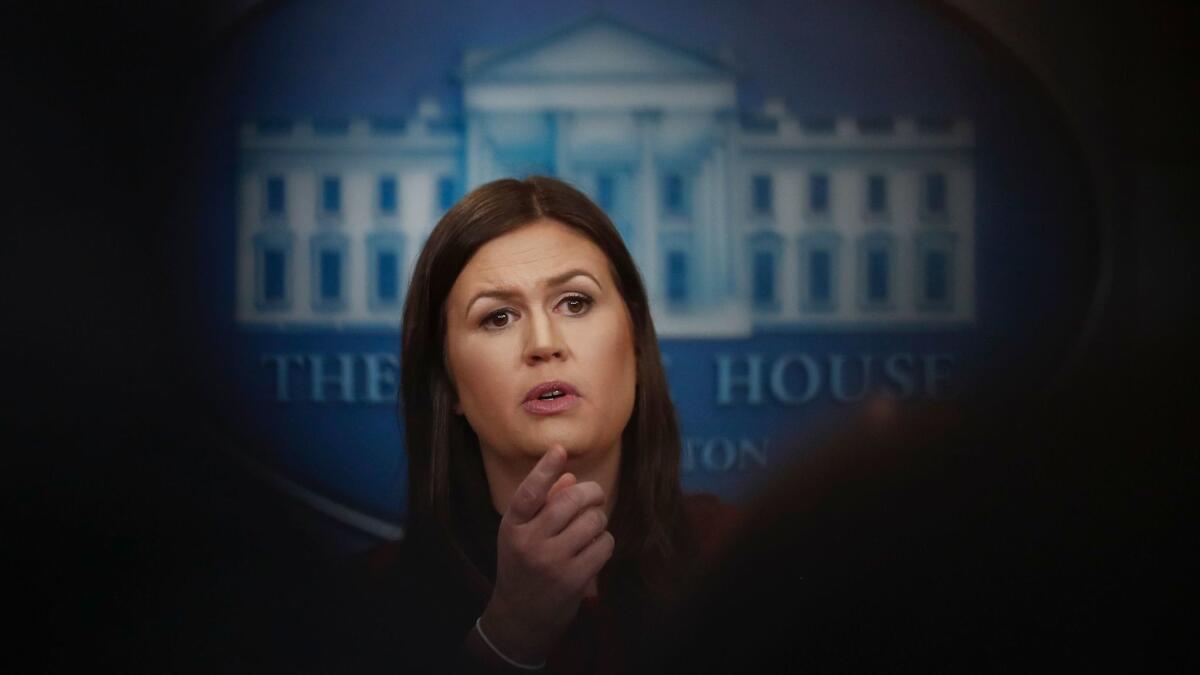 White House press secretary Sarah Huckabee Sanders, framed by reporters, speaks at the White House in Washington on Sept. 5.