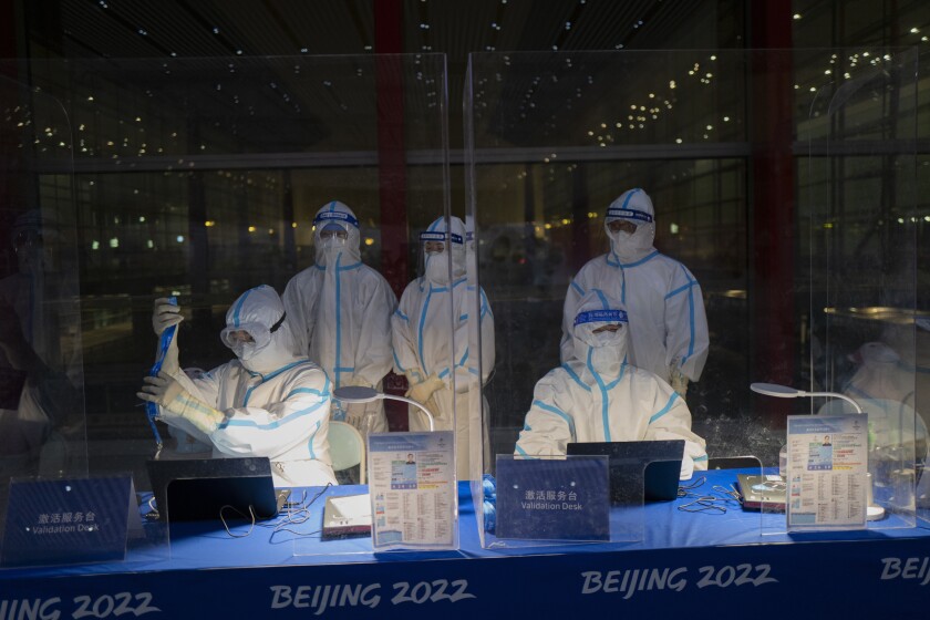 FILE - Olympic workers in hazmat suits work at a credential validation desk at the Beijing Capital International Airport ahead of the 2022 Winter Olympics in Beijing, Monday, Jan. 24, 2022. Athletes and others headed to the Olympics face a multitude of COVID-19 testing hurdles as organizers seek to catch any infections early and keep the virus at bay. (AP Photo/Jae C. Hong, File)