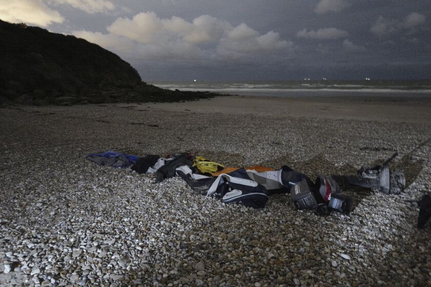 Life jackets, sleeping bags and damaged inflatable small boat are pictured on the shore in Wimereux, northern France, Friday, Nov. 26, 2021 in Calais, northern France. Children and pregnant women were among at least 27 migrants who died when their small boat sank in an attempted crossing of the English Channel, a French government official said Thursday. (AP Photo/Rafael Yaghobzadeh)
