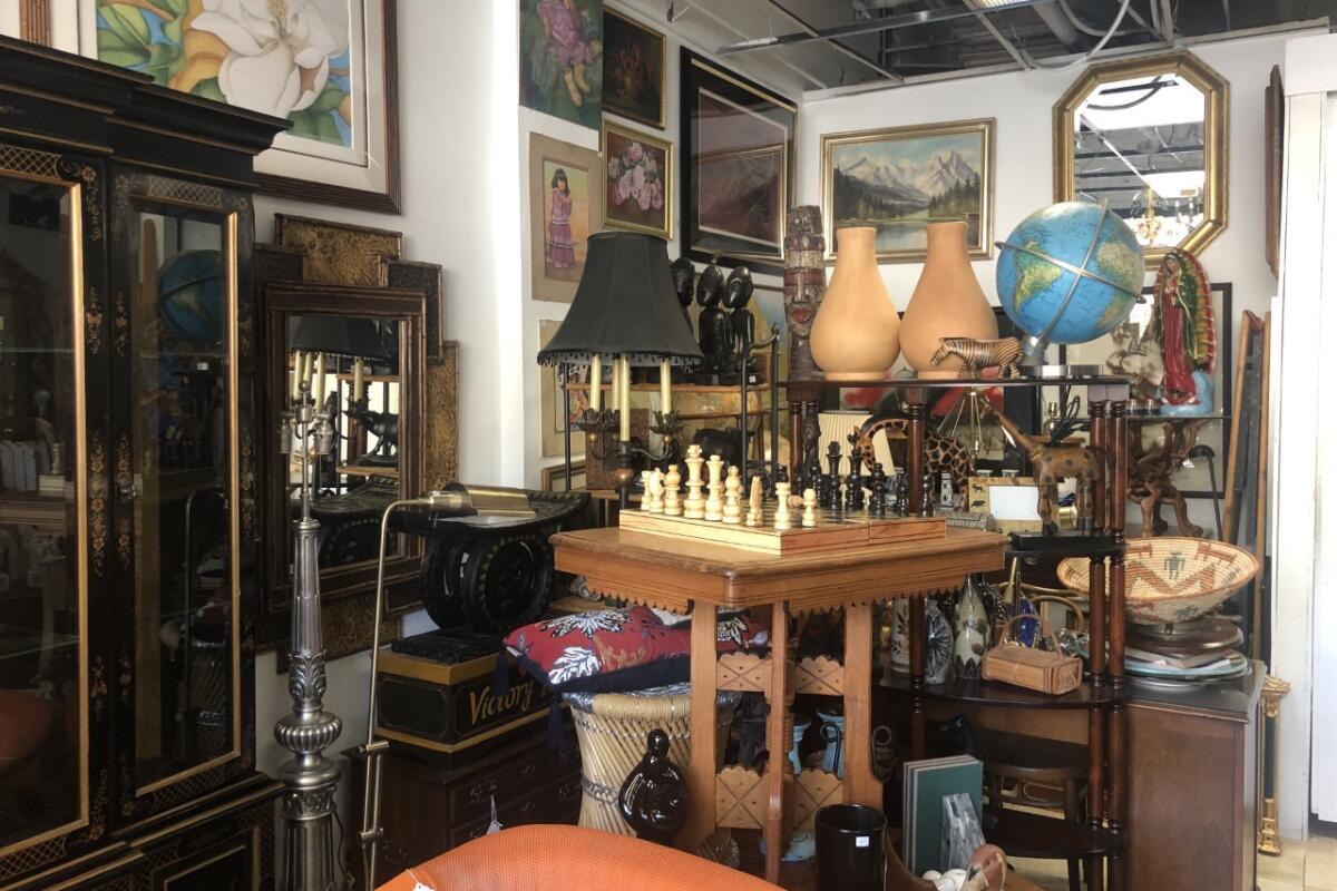 A chess set on a table amid other furnishings and paintings at Casa Victoria thrift store in Echo Park.