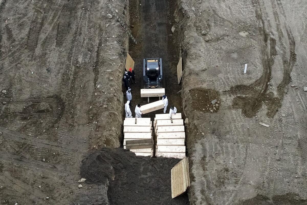 Workers bury bodies in a trench on Hart Island in the Bronx, N.Y.