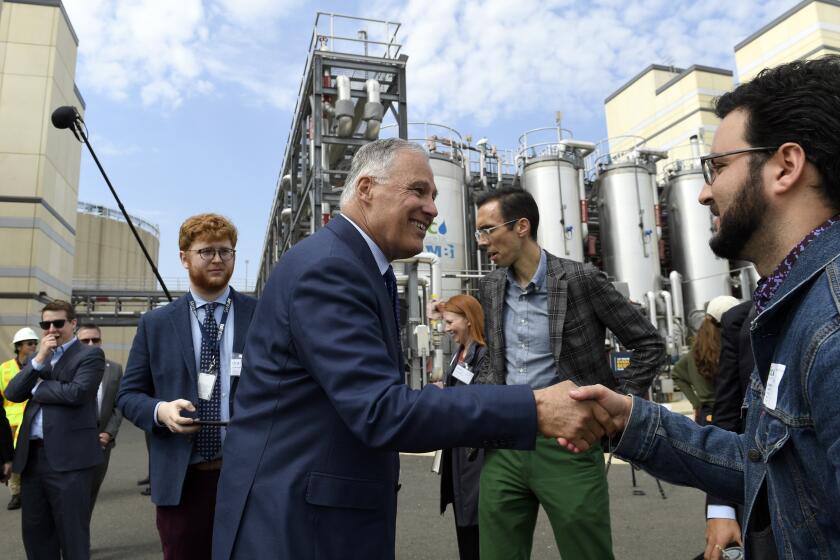 FILE - Democratic Presidential candidate Washington Gov. Jay Inslee, center, greets people as he tours the Blue Plains Advanced Wastewater Treatment Plant in Washington, Thursday, May 16, 2019, during an event where he unveiled part of his plan to defeat climate change. (AP Photo/Susan Walsh, File)