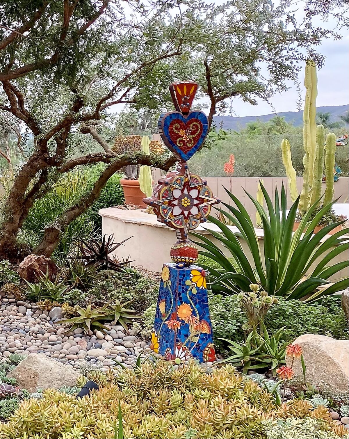 Succulents with varied leaf color and texture add interest to a garden that also has vibrant mosaics and decorative stone.