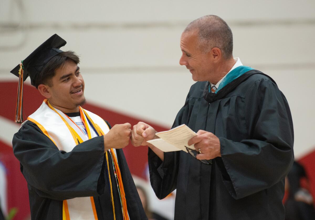 Angel Govea bumps fists with Los Amigos High Principal Todd Nirk ahead of the senior graduation ceremony on Wednesday.