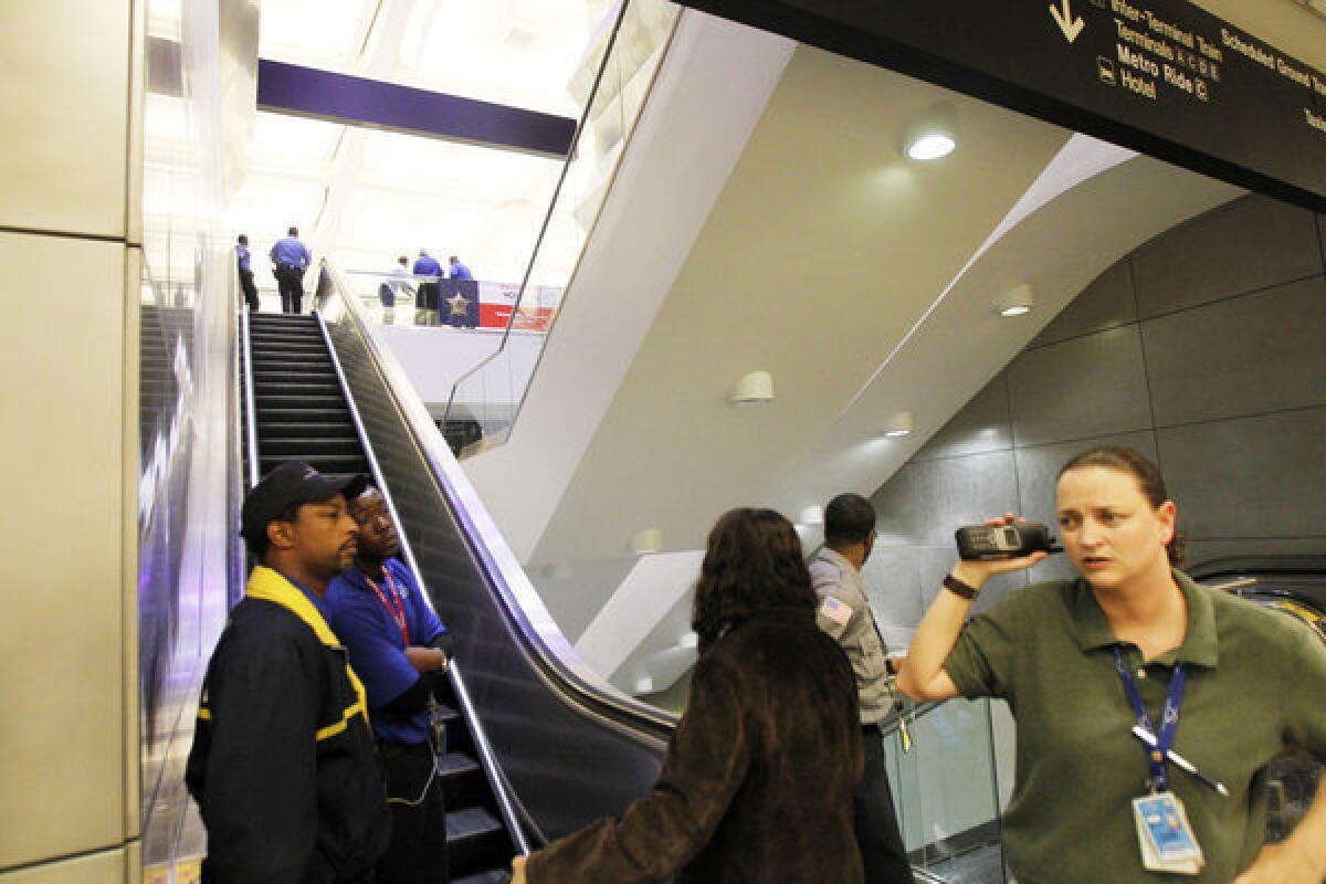 Security officials at Bush Intercontinental Airport stand at the bottom of the escalators as police investigate a shooting near Terminal B on Thursday in Houston. Authorities say a man from Beaumont, Texas, shot himself in the head.