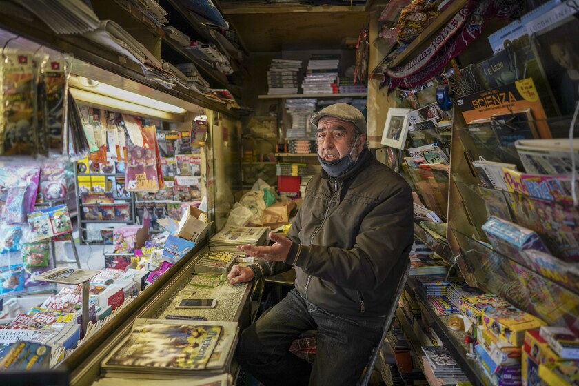 Armando Alviti, 71, sits inside his newspaper kiosk, in Rome, Friday, Dec. 4, 2020. In Italy, which has the world's second-oldest population, many people in their 70s and older have kept working through the COVID-19 pandemic. From neighborhood newsstand dealers to farmers bring crops to market, they are defying stereotypic labels that depict the old as a monolithic category that's fragile and in need of protection. (AP Photo/Andrew Medichini)