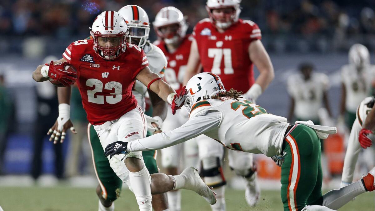 Wisconsin running back Jonathan Taylor (23) breaks a tackle attempt by Miami defensive back Sheldrick Redwine (22) during the first half of the Pinstripe Bowl.