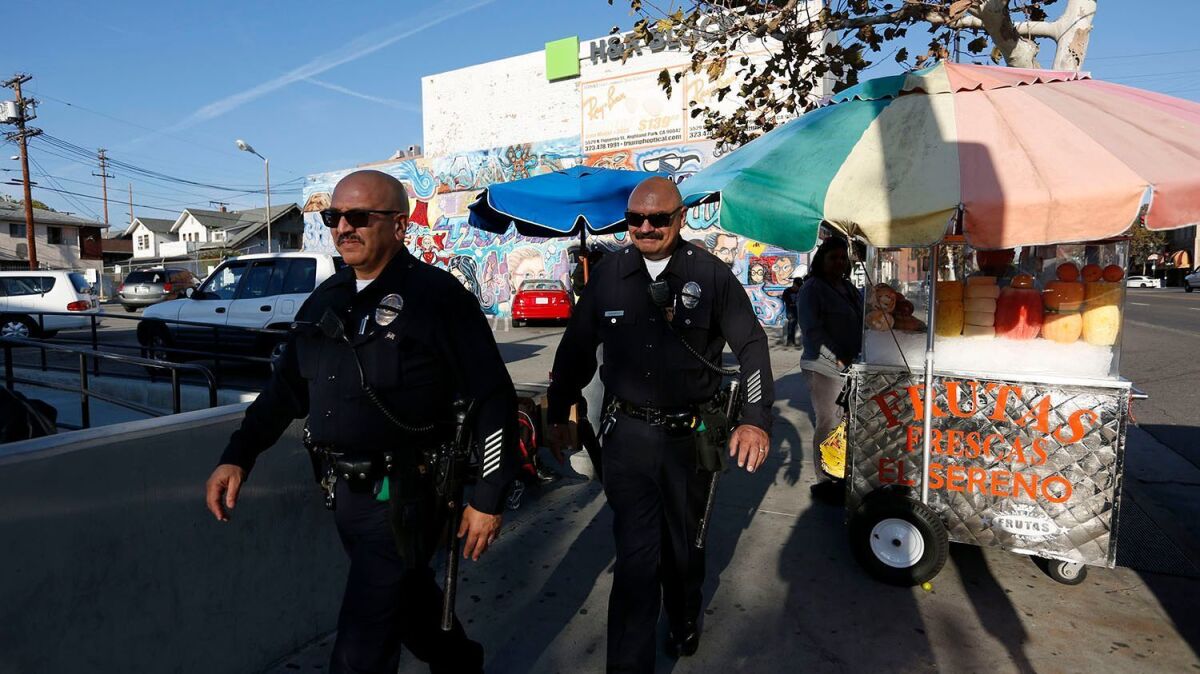 Veteran L.A. police Officer J.C. Duarte, left, on patrol with partner Harold Marinelli, says adding federal immigration enforcement to peace officers' to-do list will just drive a wedge between immigrants and law enforcement.