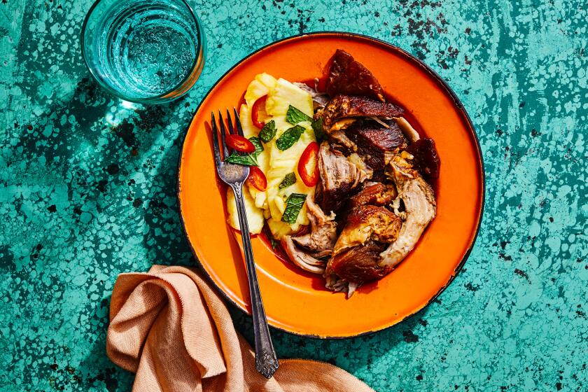 A burnished roast of pork is simmered in adobo flavorings with a lightly pickled and spicy pineapple salad on the side. Prop styling by Nidia Cueva.