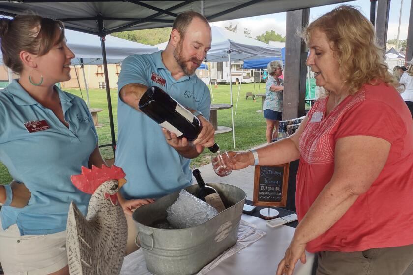 Lathom Farm and Vineyard owners Andrew and Mariah Lathom, left, pour a glass of wine for Robin Dohrn-Simpson.