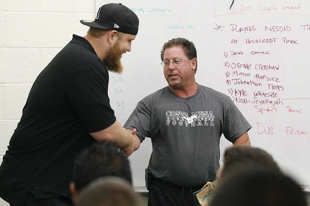 Wally Grant, the head football coach at Costa Mesa High School, shakes hands with Sam Baker, a three-time All-American tackle at USC and a current starting left tackle for the Atlanta Falcons, on Wednesday. Baker talked with Costa Mesa High football players at the school.
