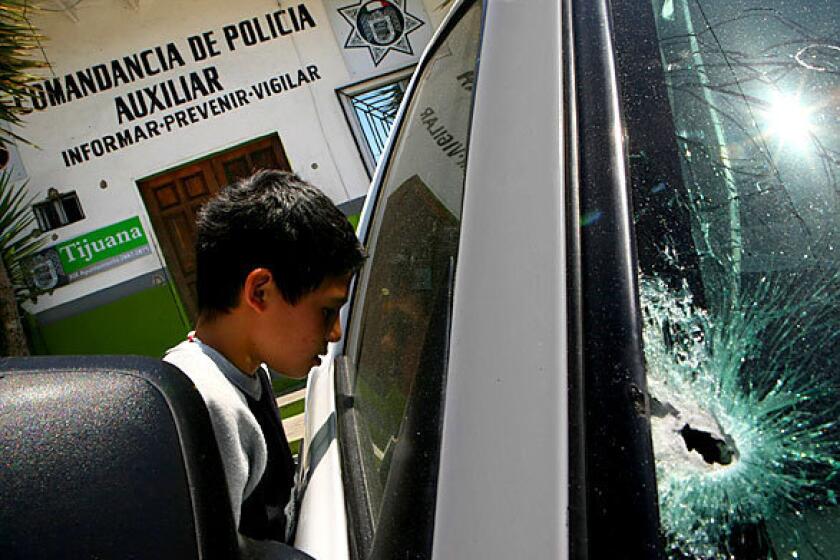 Outside a police station in the Colonia Libertad neighborhood of Tijuana, a boy peers into a police pickup damaged by gunfire. One auxiliary policeman was slain and another wounded in the attack, one of a number across the city the night before by masked gunmen that left a total of seven officers dead, and two wounded. An additional officer was injured in an earlier assault.