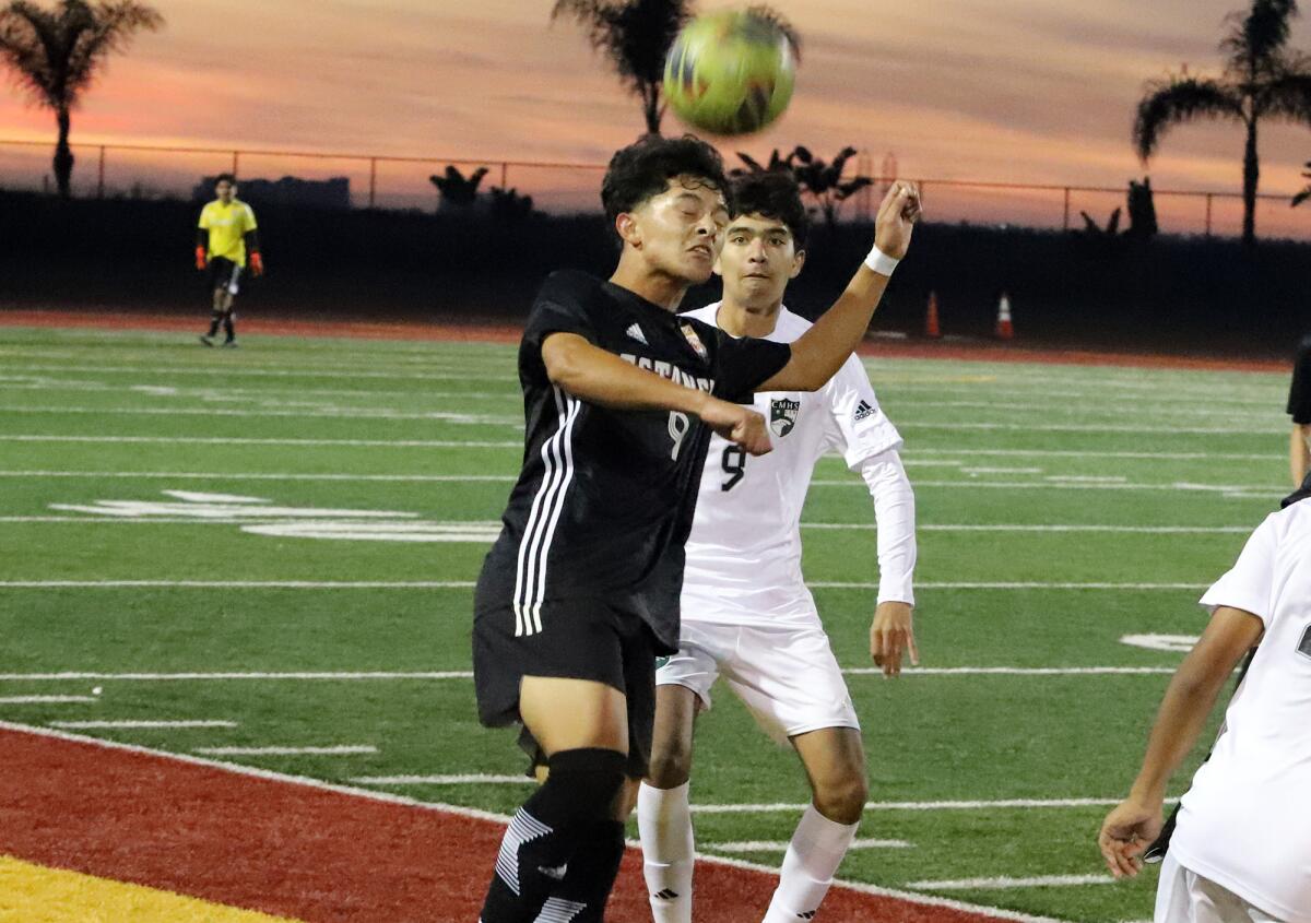 Estancia's Maynor Darastume (9) heads the ball as Costa Mesa's Jay Parra looks on in the Battle for the Bell on Friday.