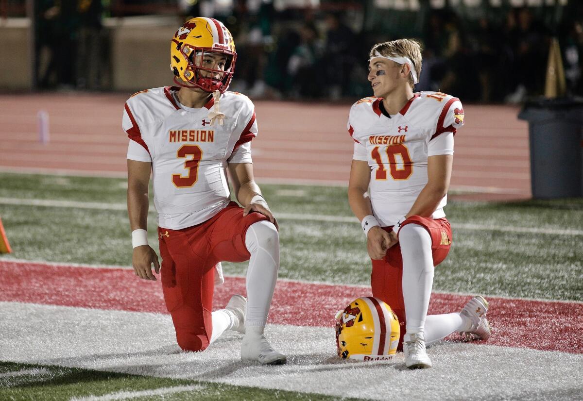 Mission Viejo quarterbacks Luke Fahey, left, and Draiden Trudeau kneel on the sideline during a timeout.