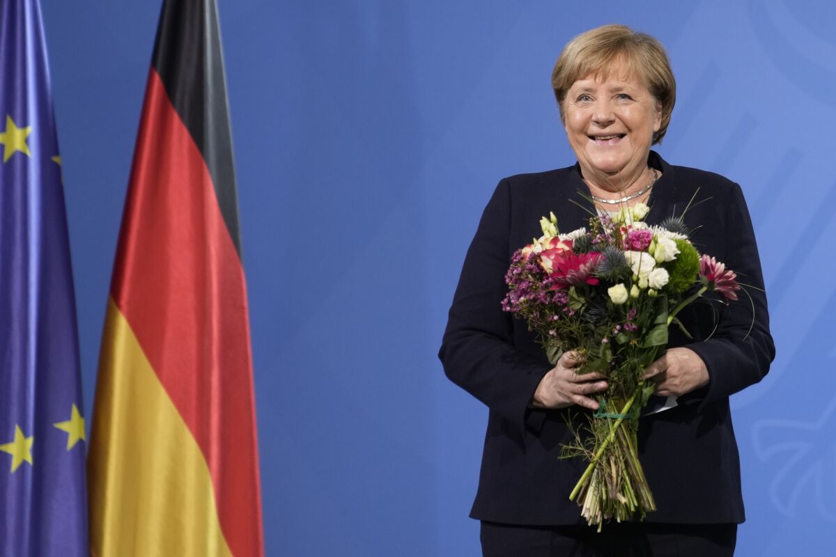 Former Chancellor Angela Merkel laughs as she receives flowers from newly elected German Chancellor Olaf Scholz during a handover ceremony in the chancellery in Berlin, Dec. 8, 2021. Merkel slammed Russia's attack on Ukraine and hinted at a possible return to the limelight in her first semi-public comments since leaving office, the country's dpa news agency reported Thursday, June 2, 2022. (Photo/Markus Schreiber, File)