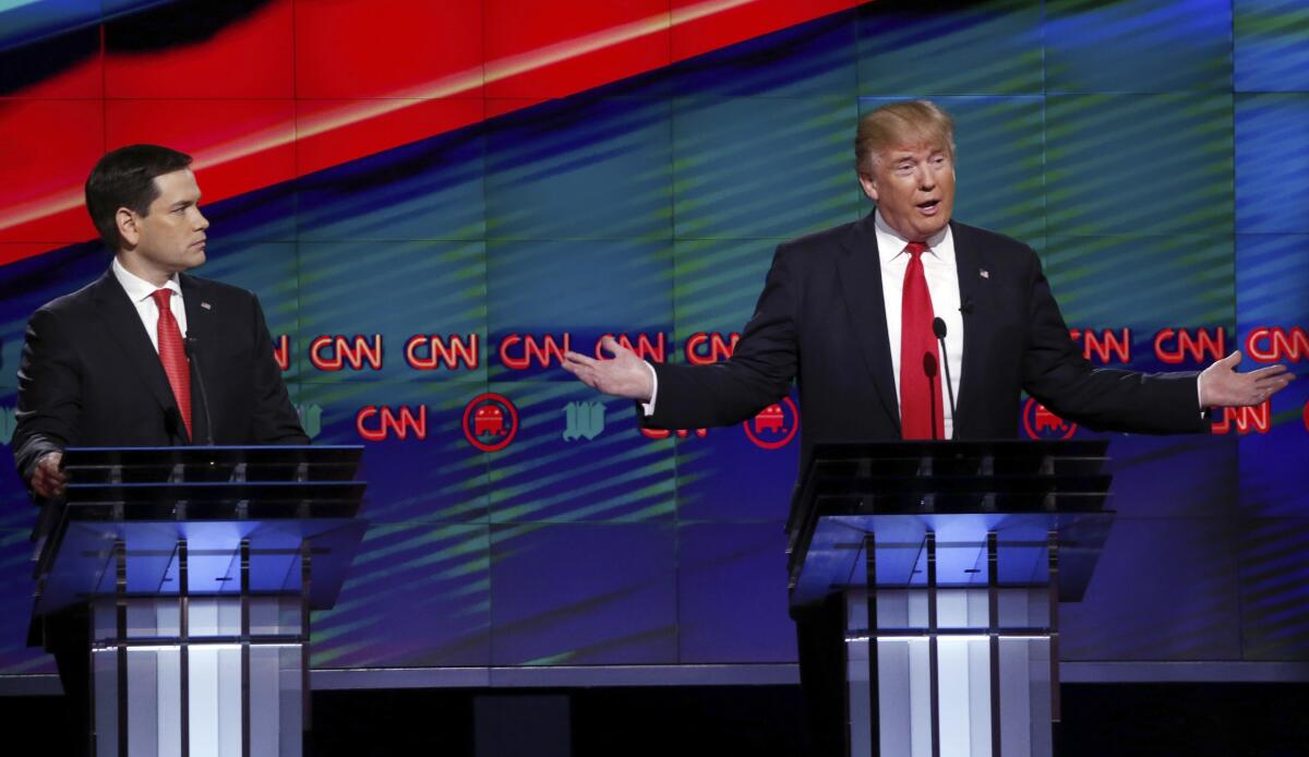Donald Trump speaks and gestures during a debate as Sen. Marco Rubio, R-Fla., listens.