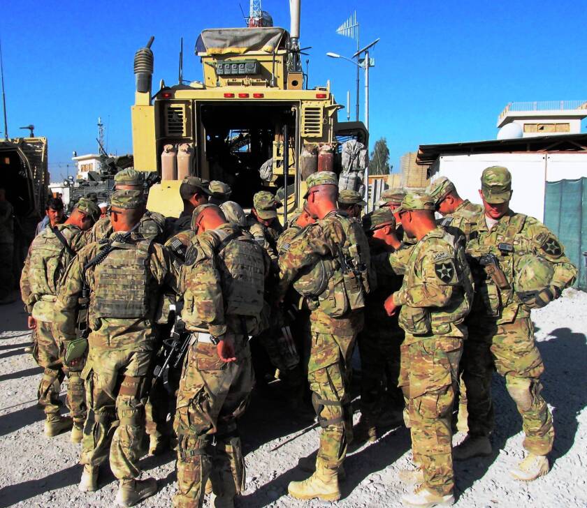 U.S. troops say a prayer for protection behind their armored vehicles before setting out on patrol, a daily ritual, in Kandahar, Afghanistan.