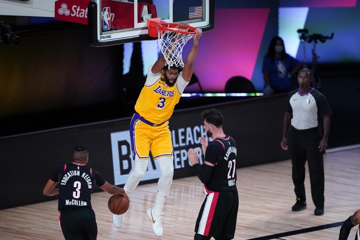 Lakers forward Anthony Davis dunks over Portland Trail Blazers center Jusuf Nurkic and guard CJ McCollum.