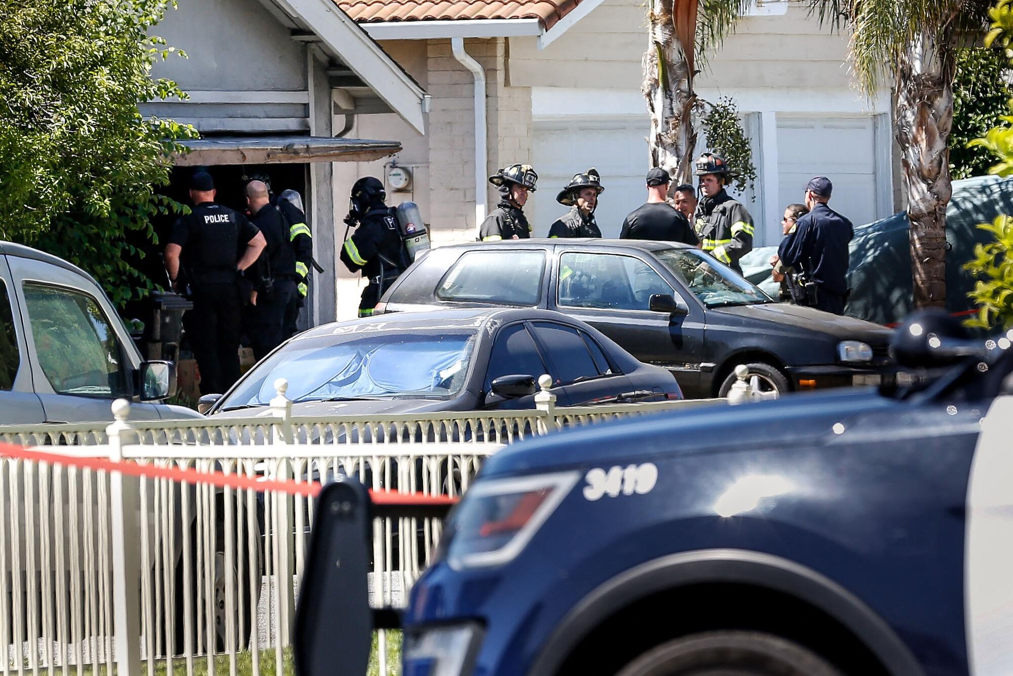 People in different official uniforms appear in front of a house.