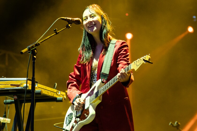 A woman in a long red coat plays a guitar