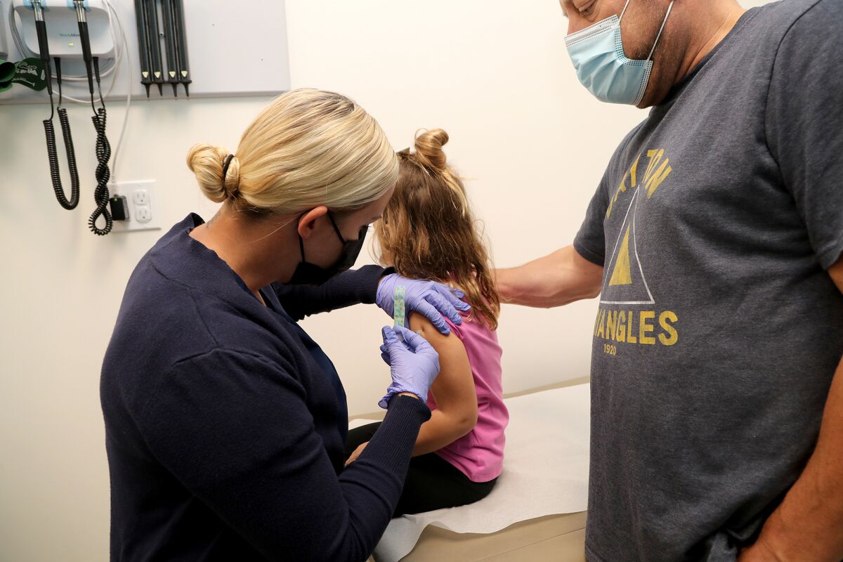 Lyndi, 5, looks away while Amanda Maxwell, the clinical nurse manager, administers a shot of a Pfizer COVID-19 vaccine.
