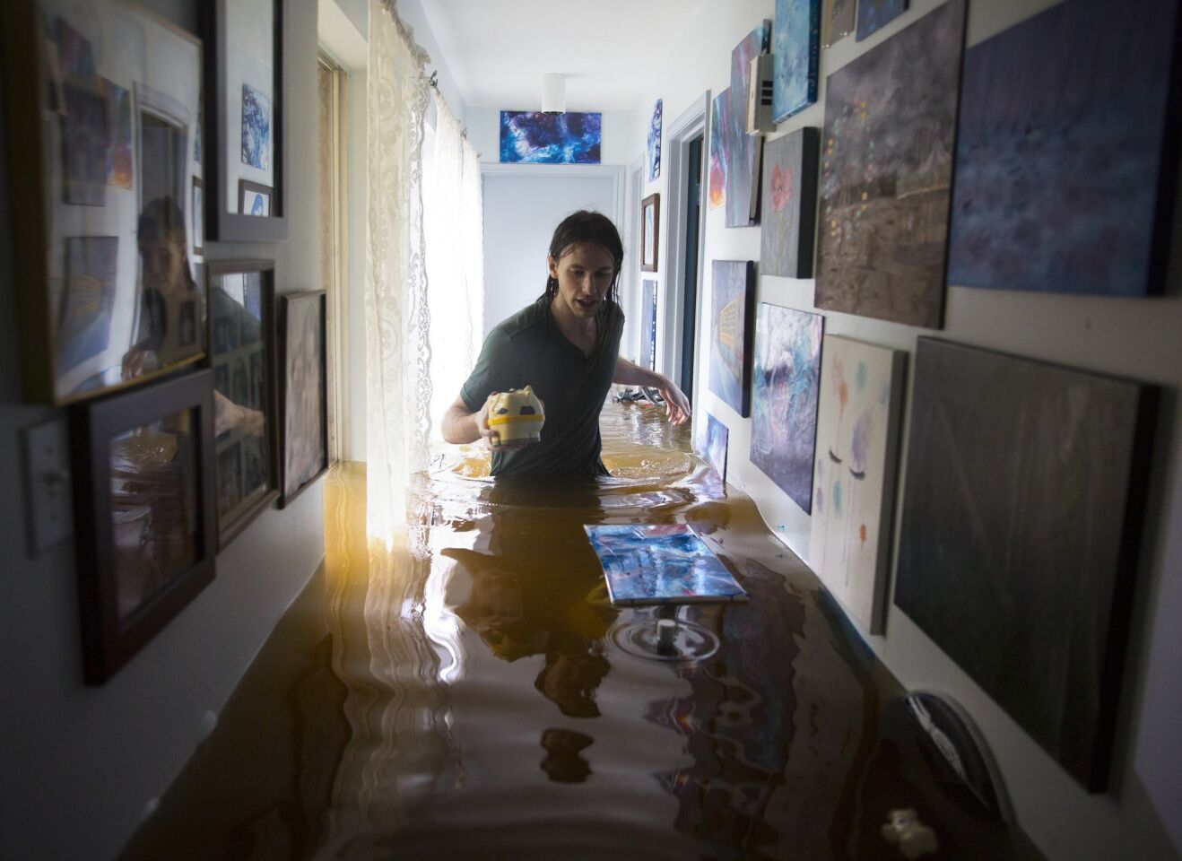 Matthew Koser looks for important papers and heirlooms inside his grandfather's house after it was flooded by heavy rains.