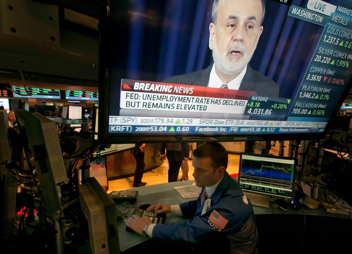 The news conference of Federal Reserve Chairman Ben Bernanke appears on a television screen at a trading post on the floor of the New York Stock Exchange on Wednesday. The Fed's Open Market Committee decided to reduce its stimulus for the U.S. economy because the job market has shown steady improvement.