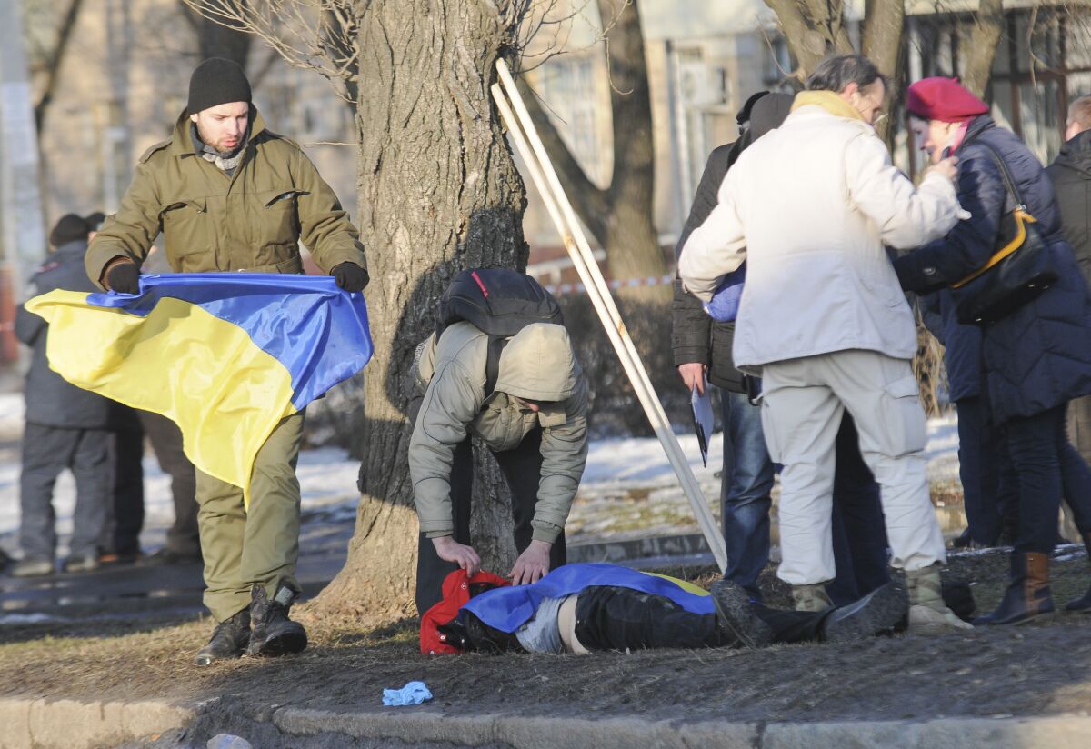 A man holds a Ukrainian flag as he prepares to help cover the body of a victim of an explosion in Kharkiv, Ukraine, on Sunday.