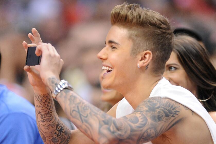 Recording artist Justin Bieber takes a photo while sitting courtside during a Clippers playoff game against the Oklahoma City Thunder.