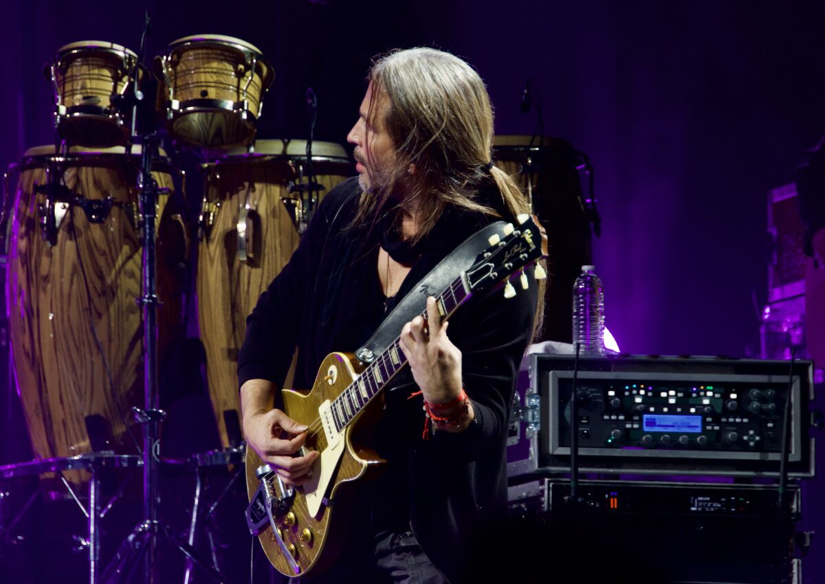 A man onstage playing the electric guitar.