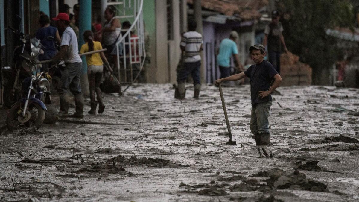 A man stands in a muddy street in Corinto, southwest Colombia, after a mudslide on Nov. 8 caused by heavy rains.