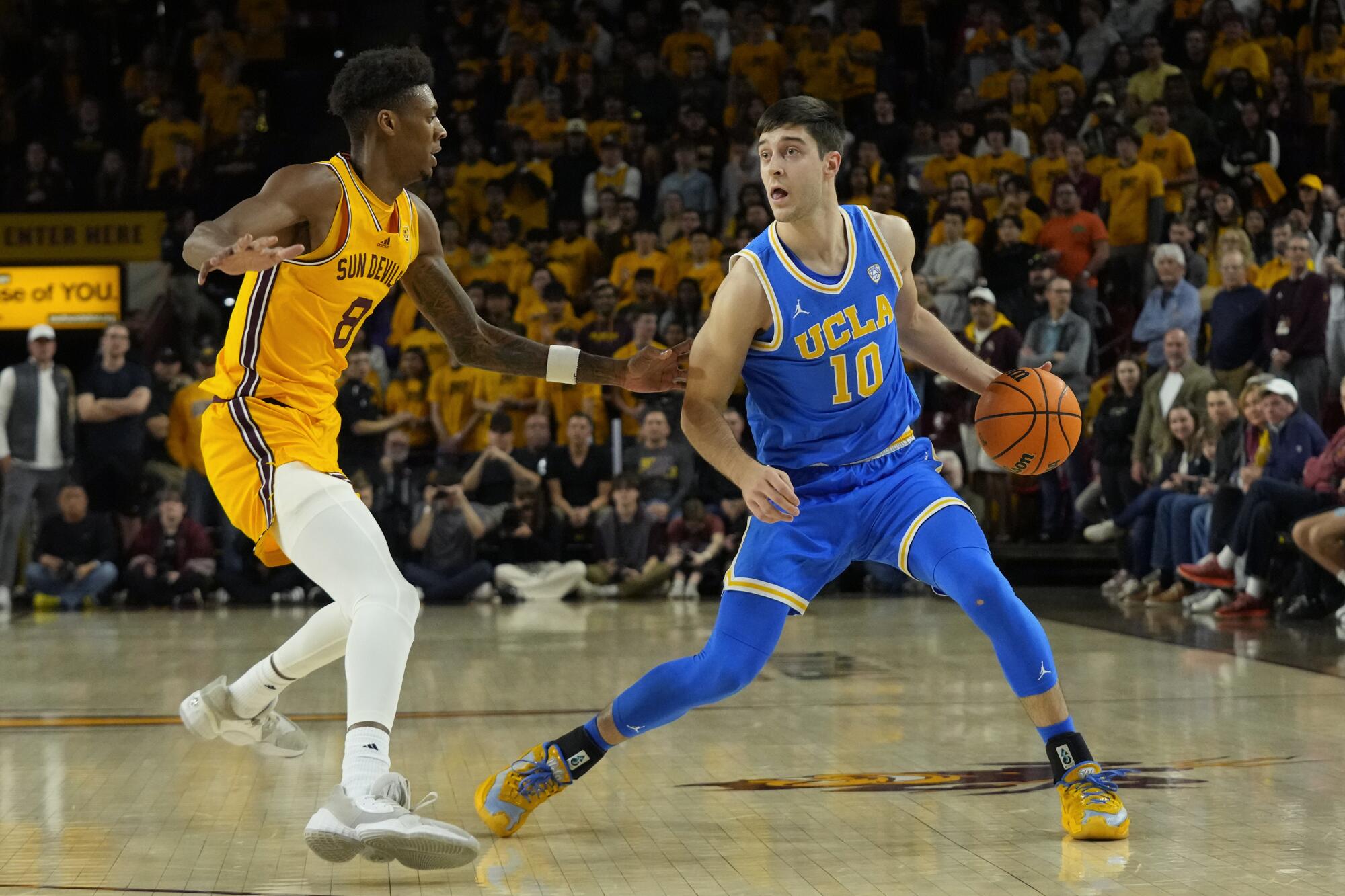 UCLA guard Lazar Stefanovic, Arizona State forveti Alonzo Gaffney'in önünde topu kontrol ediyor.