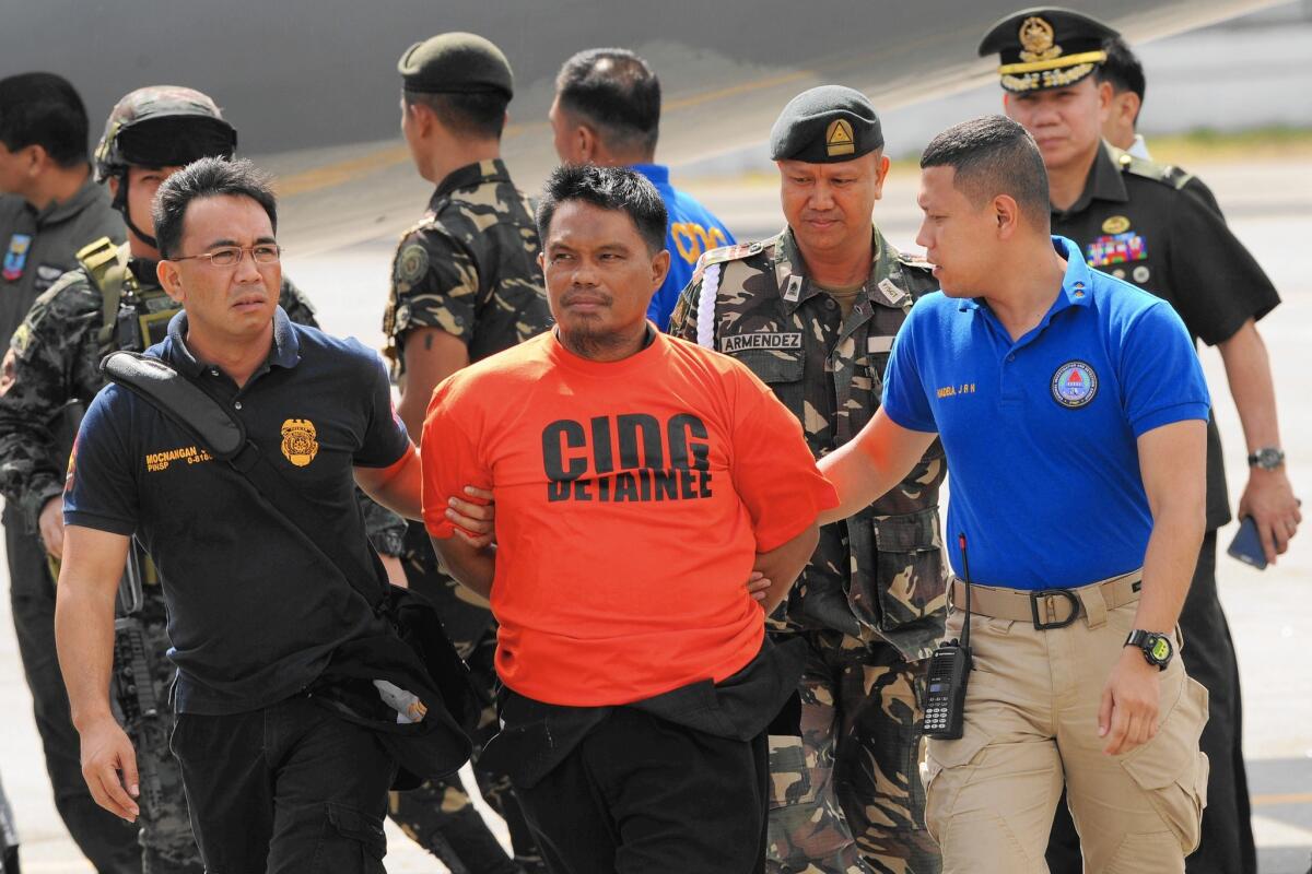 Muslim rebel leader Mohammad Ali Tambako, center, arrives at an air base in Manila in March after his arrest in Mindanao on suspicion of sheltering a suspected bomb maker.