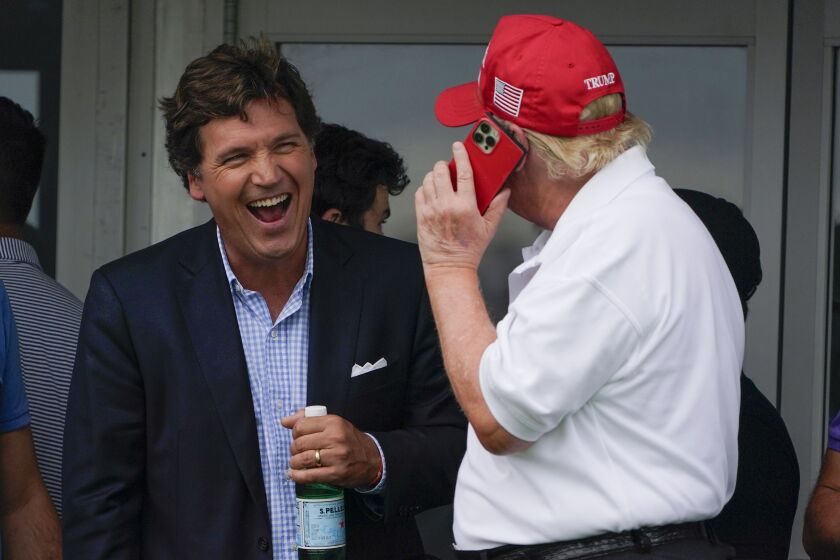 Tucker Carlson, left, talks with former President Donald Trump during the final round of the Bedminster Invitational LIV Golf tournament in Bedminster, N.J., Sunday, July 31, 2022. (AP Photo/Seth Wenig)