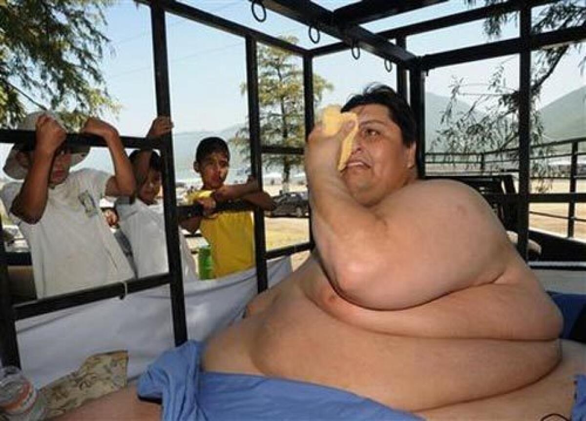 Manuel Uribe, better known as "Meme" who weights around 310 kilograms (700 pounds), wipes his face inside a trailer holding his specially designed bed on a trip to a lake while children look at him in Monterrey, northern Mexico, yesterday. Uribe, 43, who once weighed half a ton, has been largely confined to his home for the last six years.