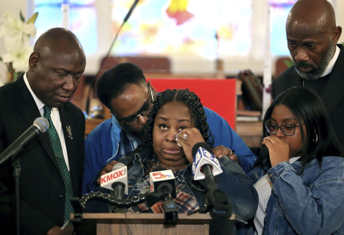 Deon January, center, wipes tears from her eyes as she talks about her son DeAndre Morrow during a news conference in Edwardsville, Ill., Tuesday, May 3, 2022. Morrow was killed when a tornado struck the Edwardsville Amazon warehouse where he worked in December 2021. January is comforted by her husband, Jerrett January, behind her, as her attorney Ben Crump, left, looks on. (David Carson/St. Louis Post-Dispatch via AP)