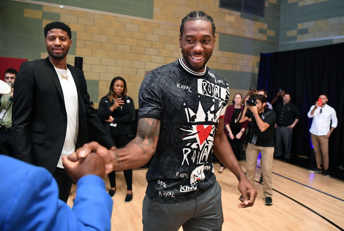 Kawhi Leonard and Paul George make their way to the stage before their introductory news conference with the Clippers.