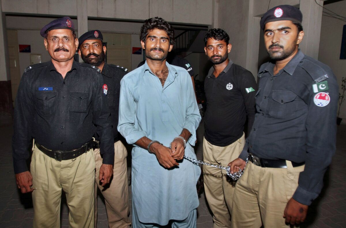 FILE - Police officers present Waseem Azeem, the brother of slain social media star Qandeel Baloch, to the media following his arrest, at a police station in Multan, Pakistan, July 17, 2016. Azeem who was sentenced to life in prison in 2019 for strangling his sister, Qandeel Baloch, was acquitted of murder Monday, Feb. 14, 2022, after his parents pardoned him under Islamic law, an attorney for the man's family said. (AP Photo/Asim Tanvee, File)