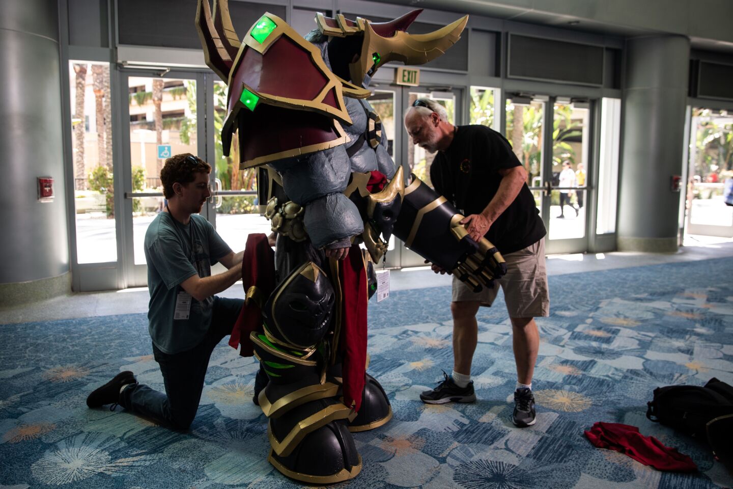 Joshua Winick, cosplaying as Fel Lord Zakuun from the game "World of Warcraft," gets help putting on his costume during the 2019 WonderCon at the Anaheim Convention Center.