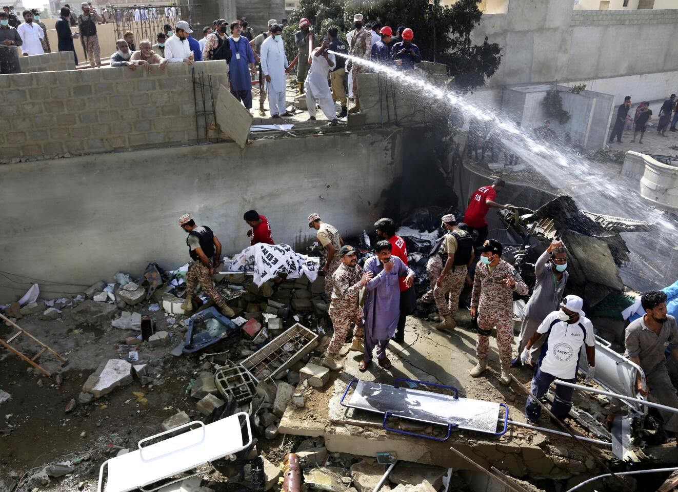 A victim's body is removed from the wreckage of a Pakistani airliner that crashed Friday in a neighborhood in Karachi.