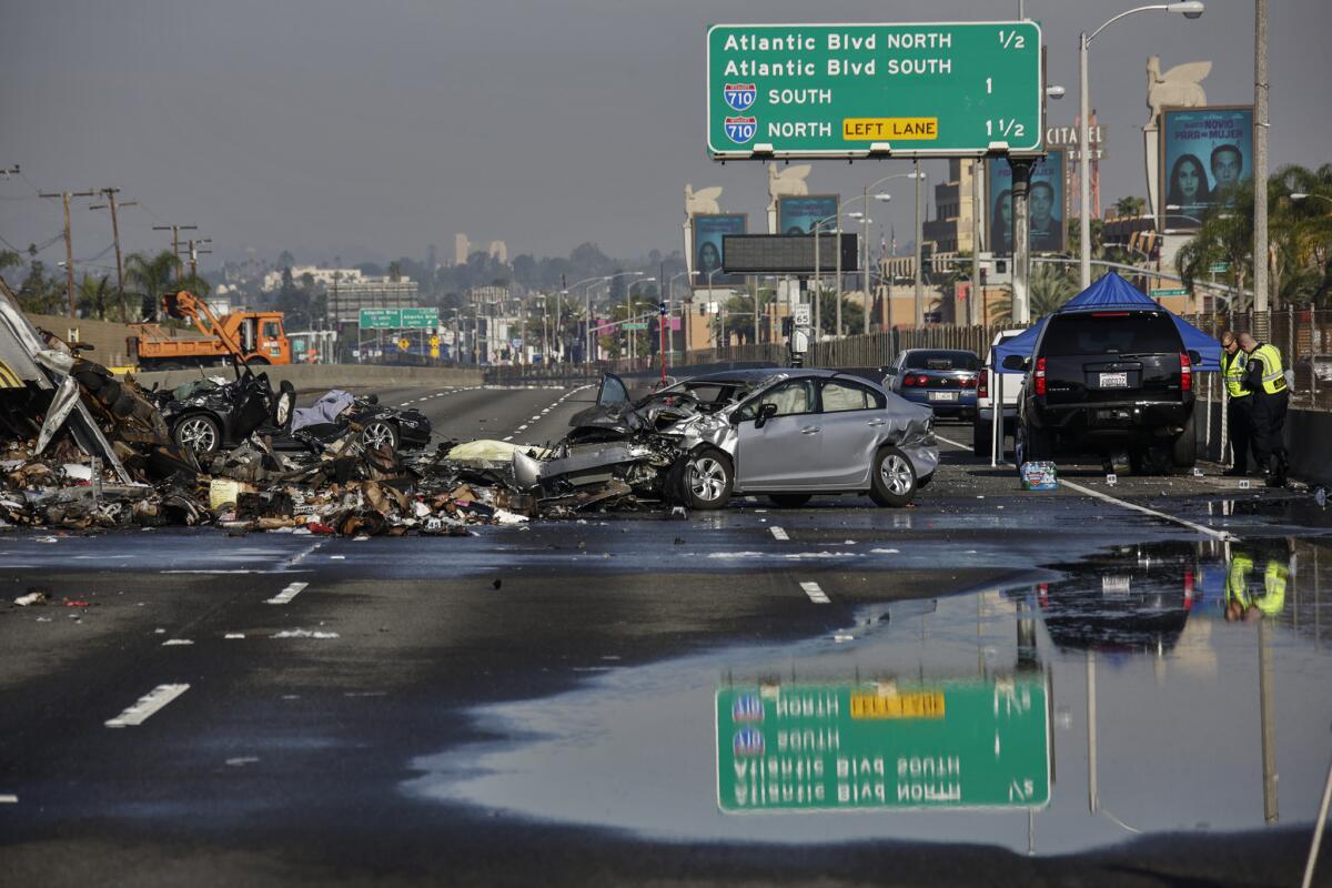 Debris is strewn across the 5 Freeway in Commerce after three people were killed in a fiery multivehicle crash. A motorist who told authorities that he had been racing was charged Tuesday with second-degree murder.