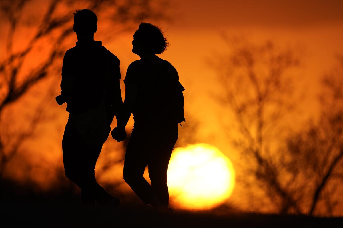 Una pareja camina por un parque al atardecer, en Kansas City, Missouri.
