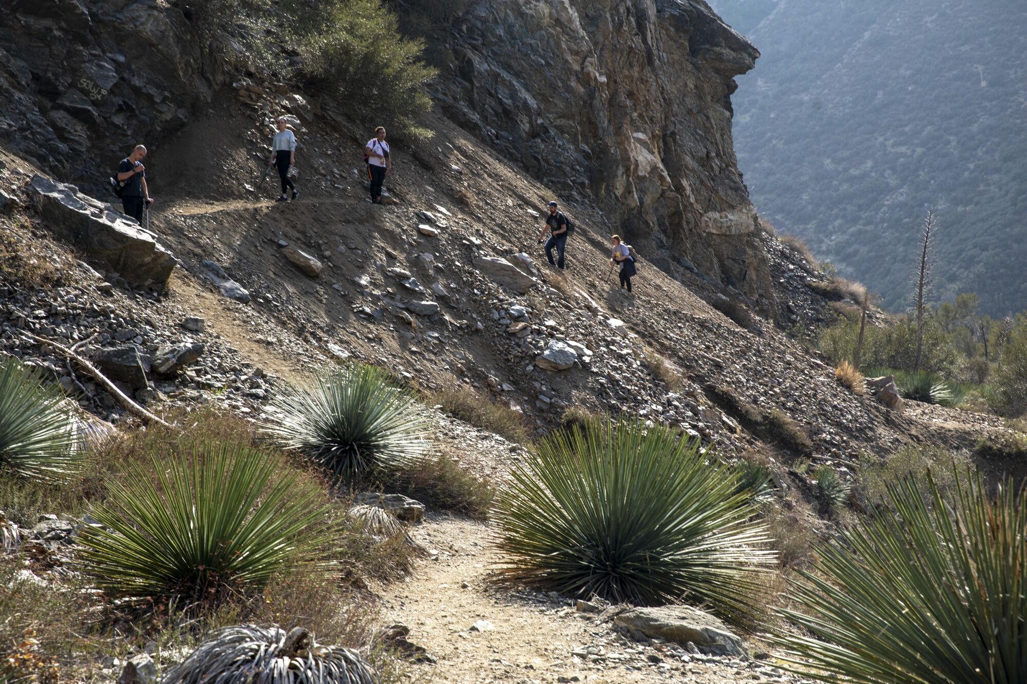 Hikers make their way along a rocky slope on the trail to the Bridge to Nowhere.