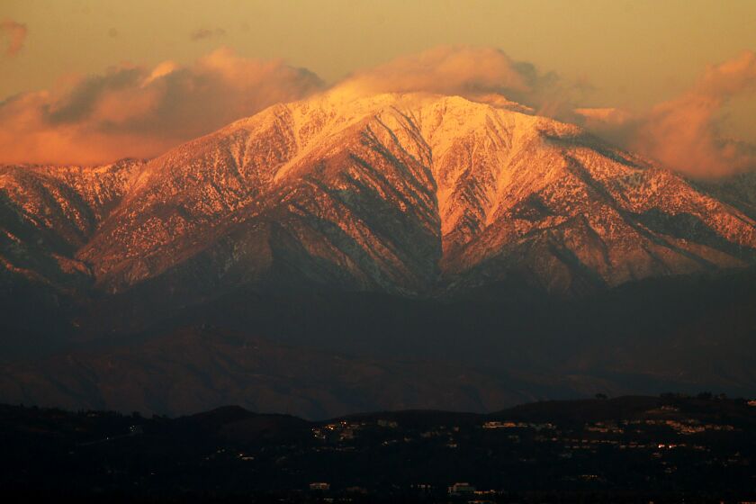 HUNTINGTON BEACH, CALIF. DEC. 24, 2016. The setting sun casts a golden glow on the snow-covered peaks of Mount Baldy on Saturday, Dec. 24, 2016. (Luis Sinco/Los Angeles Times)