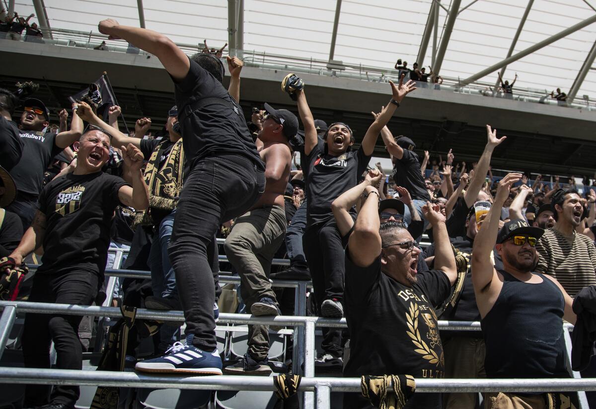 Fans celebrate a goal Saturday while watching the Los Angeles Football Club's match at Montreal on video screens inside the new Banc of California Stadium.