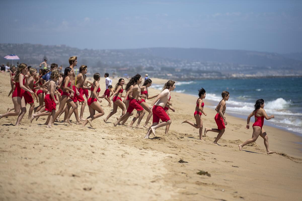 A group of Newport Beach Junior Lifeguards run into the ocean.