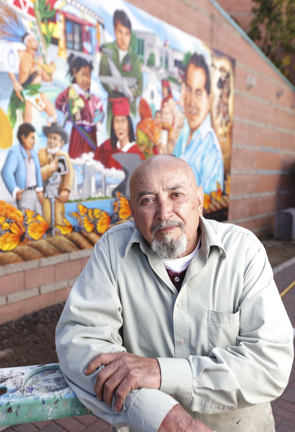 Artist Guillermo Aranda in front of a mural on the Chamber of Commerce building in National City. 
