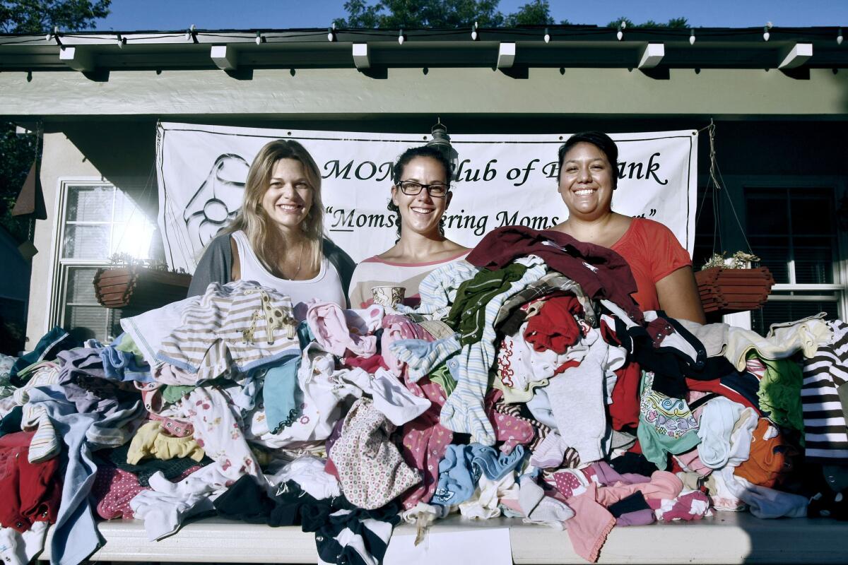 Moms Club of Burbank members, left to right, Lisa Dietrick, Karen Bowlin and Lisa Krueger, with piles of baby clothes ready to sell at their bi-annual yard sale to benefit the Mother 2 Mother Fund, in Burbank on Saturday, Sept. 14, 2013. The club had about 4,500 items, mostly for young children, for sale.